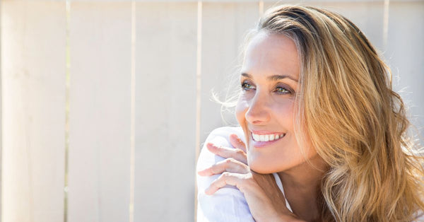 Smiling woman looking peaceful outdoors representing how does sea moss support hormone balance naturally