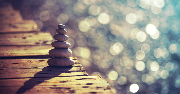 Stacked smooth stones on wooden surface symbolizing mindfulness and supplements for stress relief with calm bokeh background