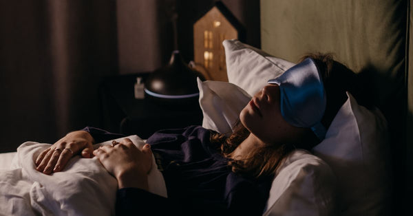 Woman sleeping peacefully with eye mask illustrating benefits of a consistent sleep routine for restful nights