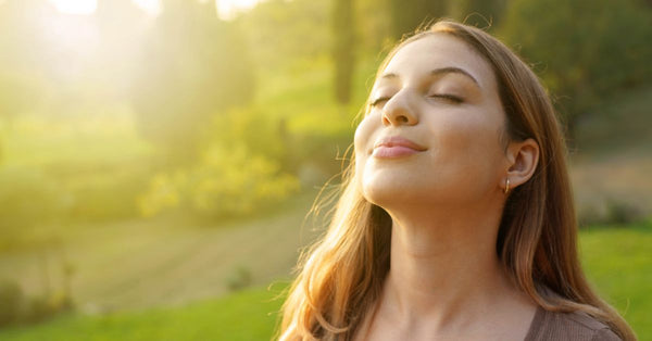 Woman practicing conscious breathwork for stress reduction outdoors in a peaceful natural setting