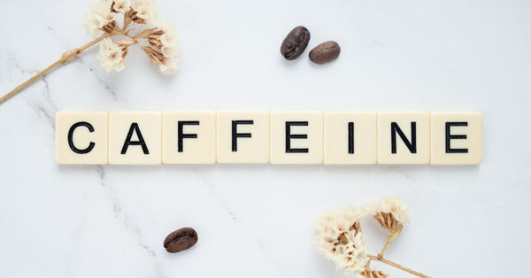 Scrabble tiles spelling caffeine with coffee beans and dried flowers illustrating how does caffeine affect sleep quality
