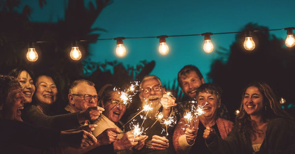 Group of family and friends celebrating outdoors with sparklers showing how to stay calm during family gatherings