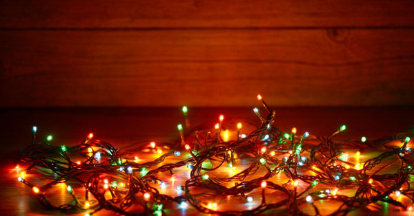 Colorful holiday string lights on wooden floor symbolizing how to get back to routine after holidays
