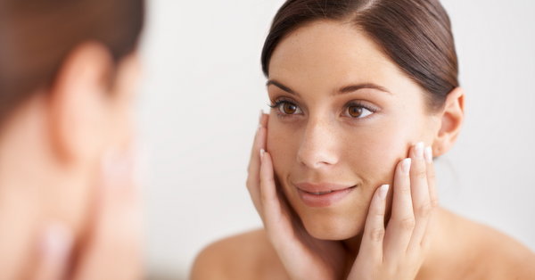 Young woman gently touching her glowing face showcasing sea moss benefits for skin and natural beauty