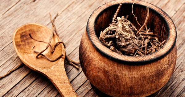 Dried valerian root in a wooden bowl with spoon showing how does valerian root work for relaxation