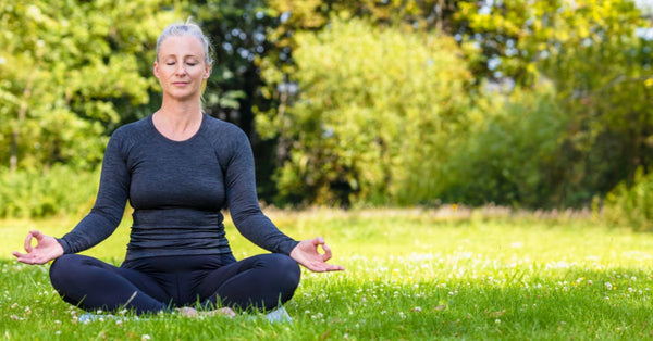 Middle-aged woman practicing meditation outdoors representing adaptogens for stress relief and calm balance