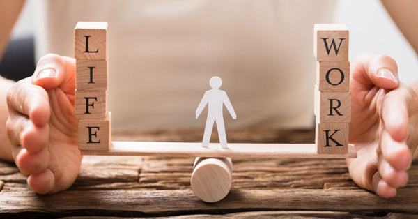 Concept of work life balance tips for busy adults shown with wooden blocks and a figure balancing on a seesaw